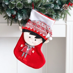 Calza di Natale rossa con elfo decorativo su un camino bianco con ghirlanda