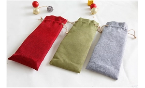 Detalle de bolsas de lino para botellas de vino con cordón en rojo y verde