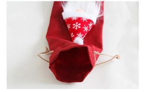Detalle de funda para vino de lino rojo con gnomo navideño y cordón de cierre rústico