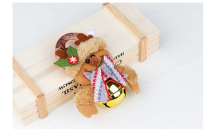 Detail eines Plüsch-Rentier-Weihnachtsschmucks mit goldener Glocke und Strickschal auf Holz
