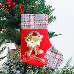 Red Christmas stocking with plush snowman and plaid trim hanging on a festive tree