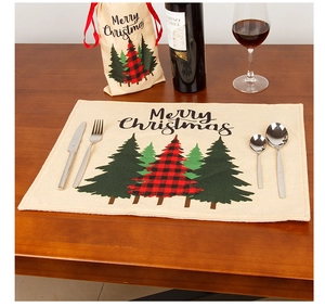 Linen Christmas placemat and wine bag set featuring festive tree patterns on wood table