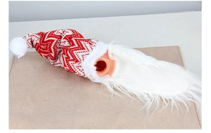 Detail of knit Christmas gnome wine bottle cover with red chevron pattern and white beard