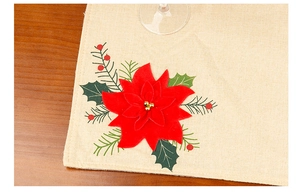 Close-up of red felt flower detail on a festive linen placemat with gold accents