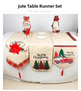 Linen Christmas table runner detail with red poinsettia, pine trees, and festive truck designs