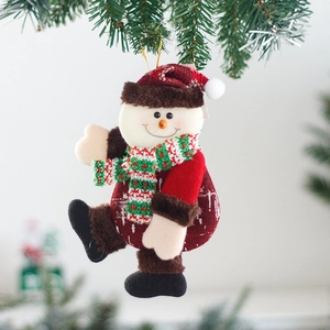 Plush snowman Christmas tree ornament with red hat and striped scarf hanging on green branches