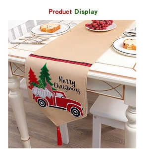 Detail of burlap Christmas table runner with gnome embroidery and festive red tassels