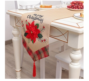 Close-up of linen Christmas table runner with red poinsettia and Merry Christmas text