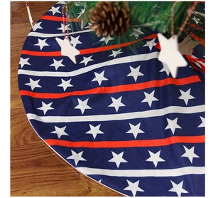 Detail of USA flag style Christmas tree skirt on wood floor with pine cones