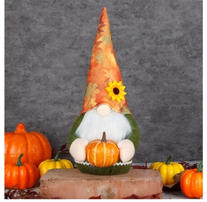 Detailed close-up of a plush fall gnome holding a pumpkin with autumn leaf decorations