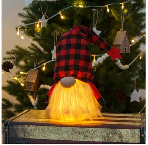 Detail eines leuchtenden Weihnachtswichtels mit rot-karierter Mütze und warmen LED-Lichtern