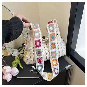 Detail of crochet tote bag with colorful floral patterns and wide shoulder strap