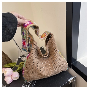 Detail of hand-crocheted straw tote featuring colorful floral patterns on shoulder straps