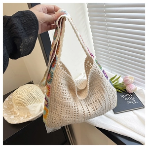Detail of hand-woven straw tote bag with colorful floral strap for summer beach fashion
