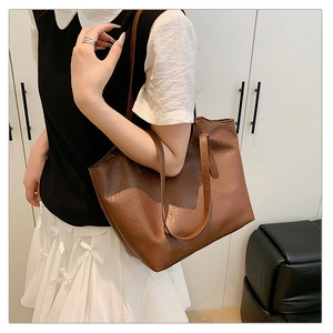 Detail of a large dark brown faux leather tote bag worn by a model for daily commuting