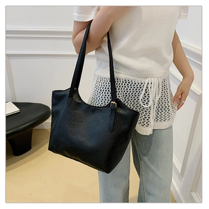 Detail of black vintage pleated faux leather tote bag showing texture and adjustable strap