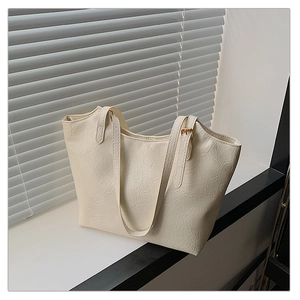 Detail of cream tote bag featuring crinkled texture and adjustable shoulder strap buckle