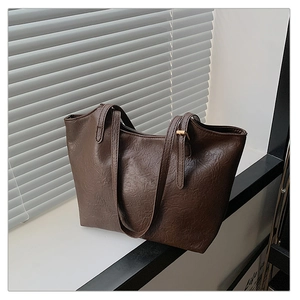 Detailed macro view of dark brown faux leather texture and gold metal buckle on tote bag