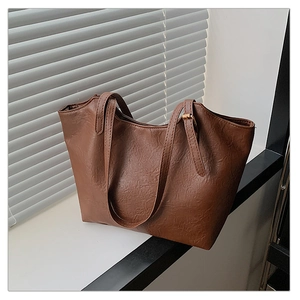 Detail of soft brown faux leather tote with textured surface and slim shoulder straps