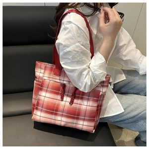 Détail d'un grand sac cabas à carreaux rouges avec cordons porté par un mannequin femme