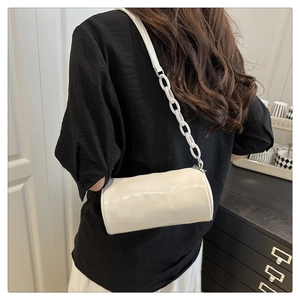 Détail du sac cylindrique blanc avec finition brillante et bandoulière à chaîne