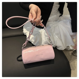 Gros plan du sac cylindrique rose avec finition brillante et détail de poignée chaîne