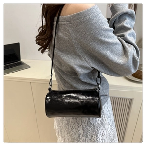 Détail d'un sac cylindrique noir brillant avec inscription blanche FASHION & BAGS