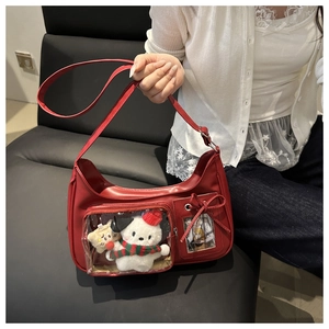 Detail of red Hobo bag with transparent PVC display pocket and plush character toy