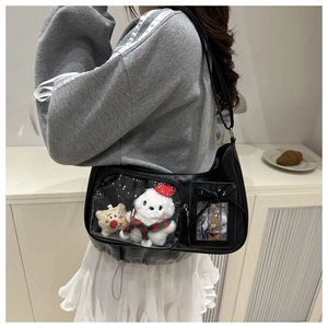 Detail of black PU ita bag featuring a clear window with plush toys and character card