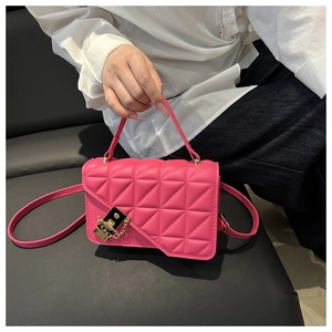 Dettaglio della borsa trapuntata rosa acceso con fibbia dorata su una camicia bianca