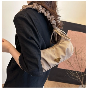 Detail of ruched shoulder strap and beige striped fabric texture on stylish hobo bag