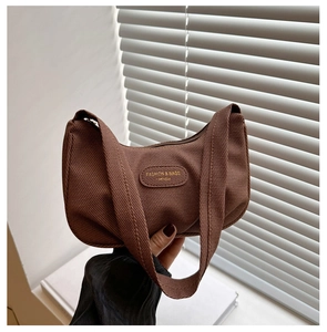 Dettaglio della borsa sottobraccio in tela marrone scuro con trama e etichetta moda