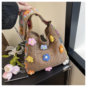 Close-up of 3D crochet flowers and rainbow patchwork strap on a knit tote bag