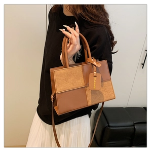Detail of color-block patchwork handbag with dual handles and metal buckle tag