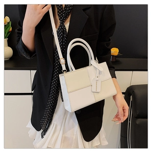 Detail of color-block leather handbag featuring white and beige geometric patchwork design
