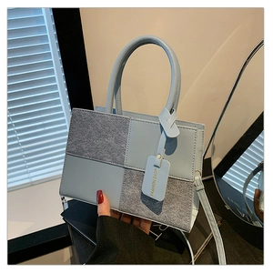 Detail of light blue and grey paneled crossbody bag with removable strap and fashion tag