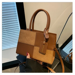 Detail of color-block patchwork tote featuring brown leather and khaki suede textures