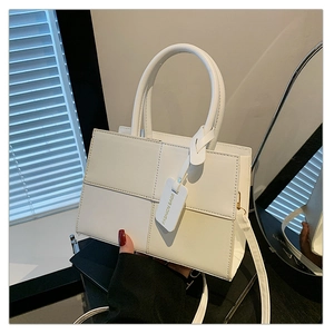 Detail of white crossbody bag featuring quilted stitching and a fashion tag