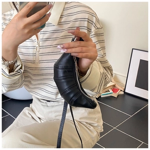 Close-up of minimalist black croissant crossbody bag with signature pleated leather seams