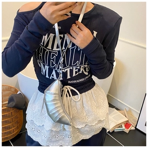 Detail of silver pleated croissant bag with metallic finish and lace dress texture