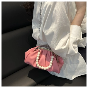 Close-up of pink pleated cloud bag featuring large pearl handle and vintage metal clasp
