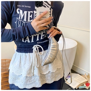 Mirror selfie showing a silver metallic mini croissant bag with pleated details