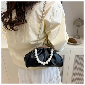 Detail of black pleated cloud bag featuring large pearl handle and silver chain strap