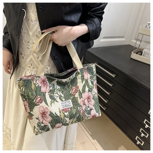 Detail of floral tapestry tote bag featuring pink blossom patterns and durable woven straps