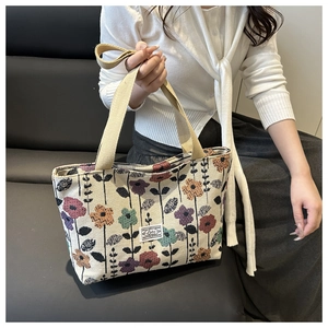 Detail of beige canvas tote bag with colorful floral jacquard and woven handles