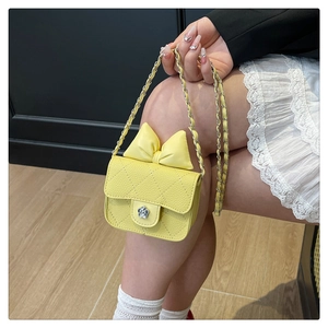 Detail of yellow quilted mini bag with oversized bow and floral metal clasp detail