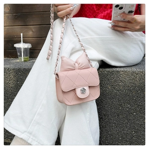 Detail of pink quilted crossbody bag with bow accent and flower-shaped silver clasp