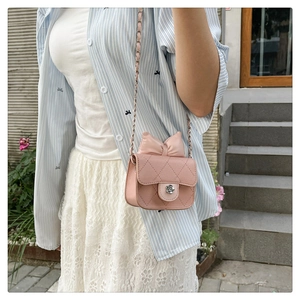 Detail of pink quilted crossbody bag featuring a decorative bow and silver flower clasp