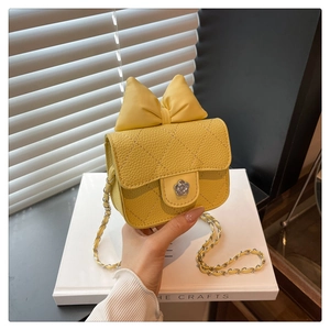Detail of yellow quilted mini crossbody bag with a large bow and floral silver clasp