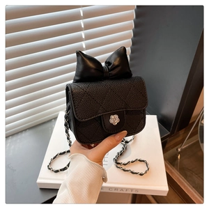Macro detail of black quilted leather mini bag with bow accent and floral silver clasp